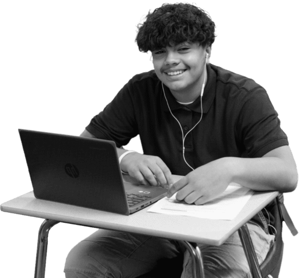 Image of a happy boy sitting at his desk with a computer in front of him.